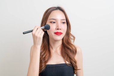 Beyaz arka planda makyaj fırçası olan güzel bir Asyalı kadın portresi