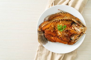 Tabakta sarımsaklı kızarmış deniz levreği balığı.