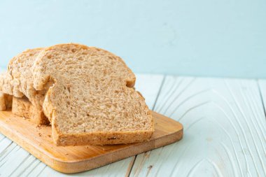 Tahta bir masada dilimlenmiş kepekli ekmek.