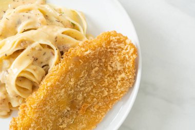 Ev yapımı fettuccine makarna beyaz krema soslu kızarmış balık.