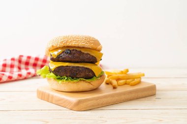 Peynirli ve patates kızartmalı hamburger veya sığır burger. Sağlıksız yemek tarzı.