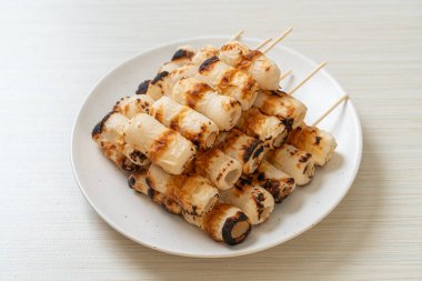 Izgara tüp şeklinde balık ezmeli kek ya da tabakta mürekkep balığı şişi.