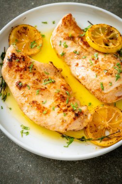 Beyaz tabakta tereyağlı ızgara tavuk, limon ve sarımsak.