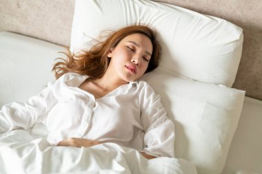 Beyaz yastıkla uyuyan güzel Asyalı kadın portresi.