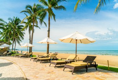 Güzel tropikal plaj ve deniz şemsiyesi ve sandalyesi otel tatil ve tatil için yüzme havuzunda.