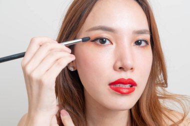 Beyaz arka planda makyaj fırçası olan güzel Asyalı kadın portresi.