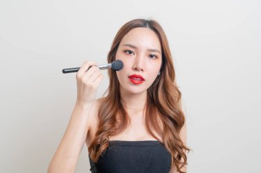 Beyaz arka planda makyaj fırçası olan güzel bir Asyalı kadın portresi
