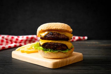 Peynirli ve patates kızartmalı hamburger veya sığır burger. Sağlıksız yemek tarzı.