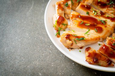 Izgara ballı tavuk göğsü. Beyaz tabakta dilimlenmiş.