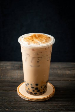 Tahta masada yanmış köpüklü ve peynirli Tayvan sütü çayı.