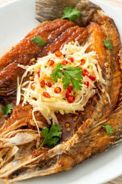 Balık soslu kızarmış deniz levreği balığı ve tabakta baharatlı salata.