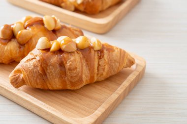 Macadamia ve ahşap tabakta karamel ile kruvasan.
