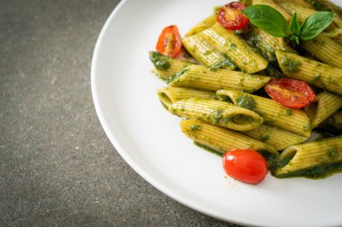 Pesto soslu ve domatesli makarna. Vejetaryen ve vejetaryen yemek tarzı.