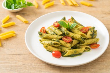 Pesto soslu ve domatesli makarna. Vejetaryen ve vejetaryen yemek tarzı.