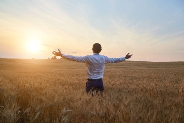 Farmer agronomist in the field raises his hands, rejoicing at the harvest, thanks God for the good weather.