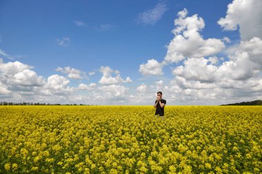 Adam burnunu kapatır ve çiçekli sarı tarlada hapşırır. Polenlere karşı uyarı.