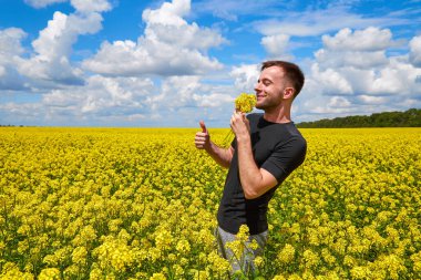 Çiftçinin elinde bir dal kolza tutan adam kokuyu içine çekiyor..