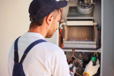 Gaz kazanının onarımı ve ayarlanması için müşteri hizmetleri. Usta gaz basınç göstergesini kontrol ediyor.