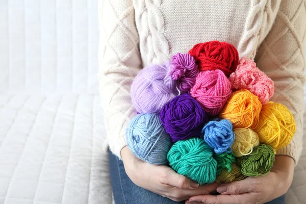 Frau, die auf der Couch sitzt und ein buntes Garn in der Hand hält. Gestricktes — Stockfoto