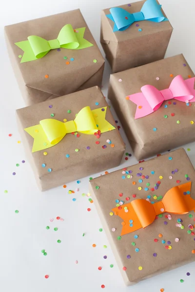 Presentes embrulhados em papel kraft. Arcos de papel brilhante colorido . — Fotografia de Stock