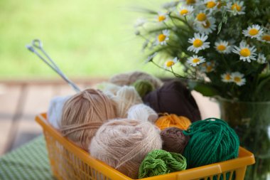 Topları ve skeins masada bir sepet içinde yalan. Renkli iplik için 