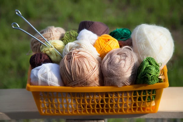 Masanın üzerinde bir sepet içinde toplar ve skeins yalan.