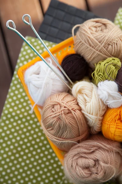 Balls and skeins lie in a basket on the table. — Stock Photo, Image