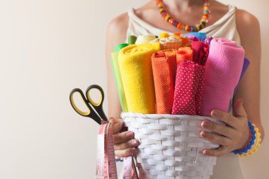 Bir kadın parlak renkli kumaş dikiş ve makas tutan.