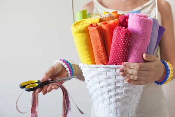 Uma mulher segura tecidos coloridos brilhantes para costura e tesoura . — Fotografia de Stock