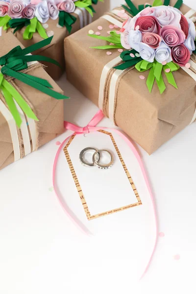 Regalos decorados con flores de papel rosa. Anillos de boda en oro blanco . — Foto de Stock