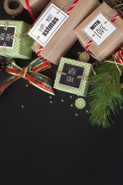 Noel hediyeleri kahverengi Kraft kağıt sarılı. Siyah arka plan. Bir Noel ağacı dalı. Kırmızı kurdele.