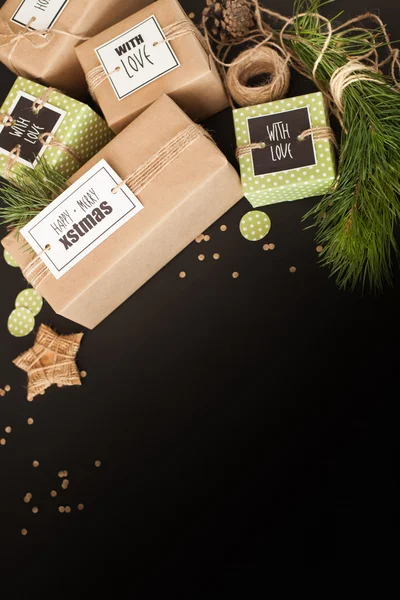 Geschenken verpakt in bruin Kraft papier op een zwarte achtergrond. De br — Stockfoto