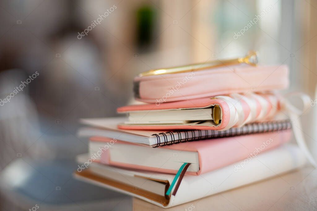 Stylish designed coral and white coloured stack of diaries with gold pen. Organiser and planner addicted people. Choosing and sorting journals.