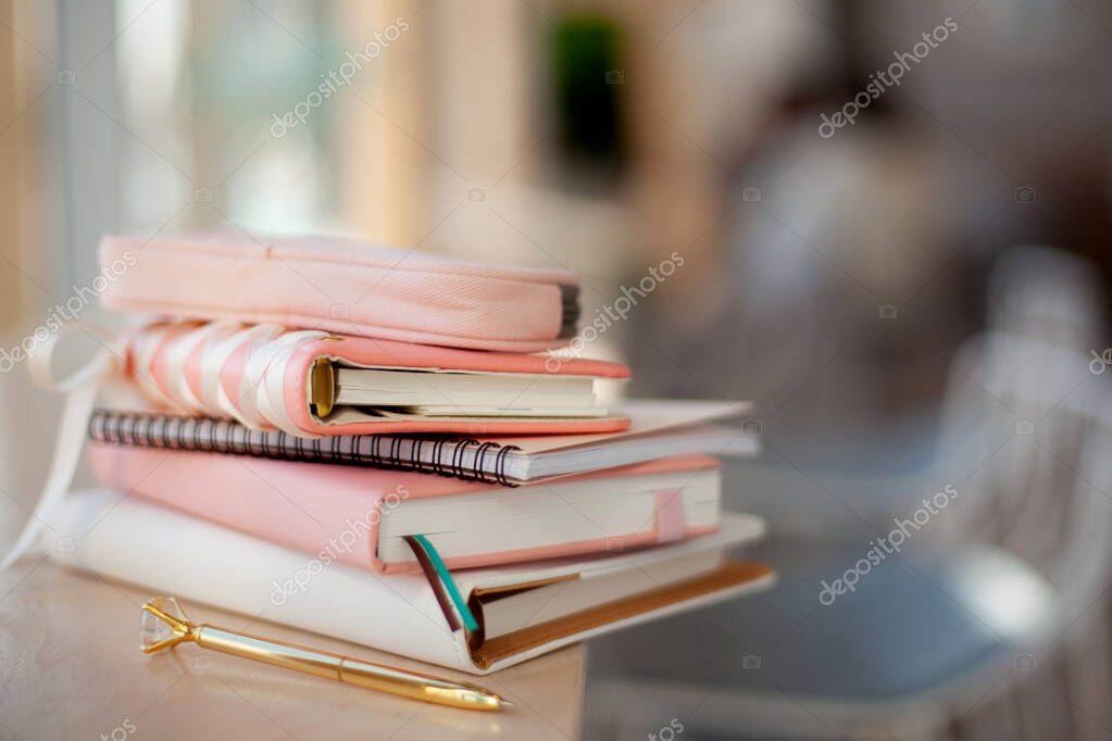 Stylish designed coral and white coloured stack of diaries with gold pen. Organiser and planner addicted people. Choosing and sorting journals.