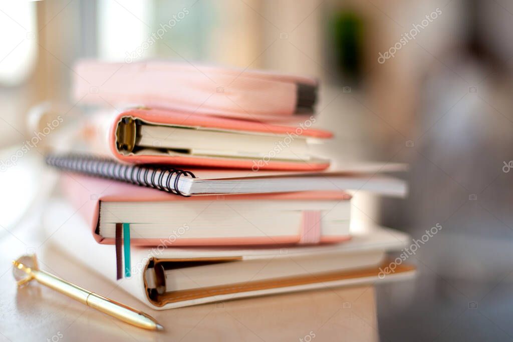 Stylish designed coral and white coloured stack of diaries with gold pen. Organiser and planner addicted people. Choosing and sorting journals.
