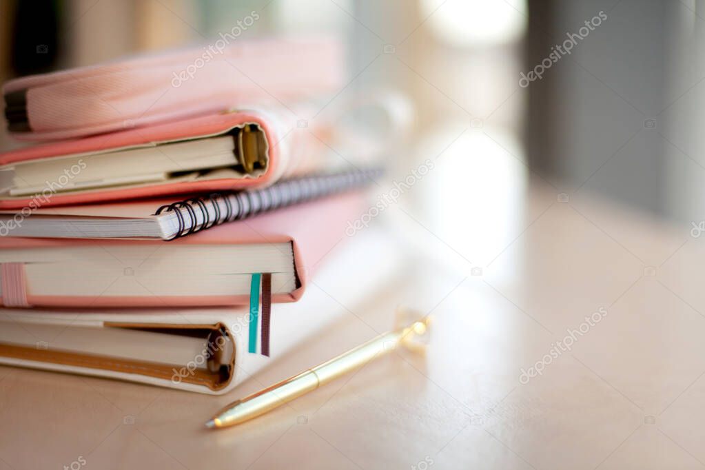 Stylish designed coral and white coloured stack of diaries with gold pen. Organiser and planner addicted people. Choosing and sorting journals.