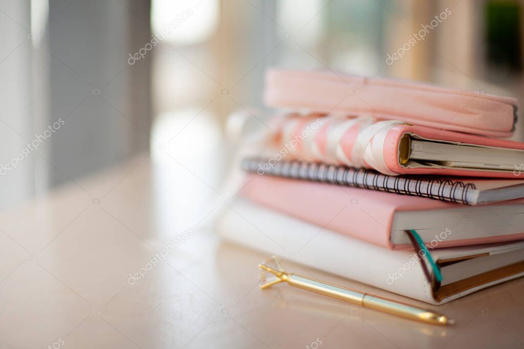 Stylish designed coral and white coloured stack of diaries with gold pen. Organiser and planner addicted people. Choosing and sorting journals.