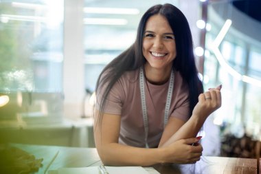 Güzel genç bayan tasarımcı dikiş atölyesindeki not defterine kıyafet ölçülerini not alıyor. Tekstil ile birlikte not defterine kadın terzi ölçümü ve çalışma planı.
