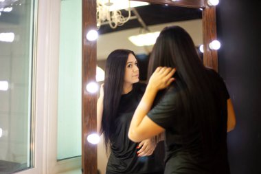 Genç bayan tasarımcı atölyede aynanın önünde göğsünü mezurayla ölçüyor. Kadın terzi elbise dikmek için vücut ölçülerini alıyor. Terzi hizmeti kavramı.