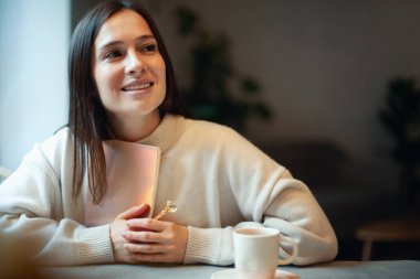 Pencereden bakıp mercan renkli bir günlük tutan 2021 'den esinlenilmiş genç bir kadın. Umut ve ilham konsepti. Hanımefendi gülümsüyor ve yeni yılı hayal ediyor. Mutluluk ve başarı.