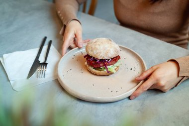 Kadın elleri pancar kökü, mercimek ve glütensiz kızarmış ekmeğe kırmızı lahana ile vejetaryen burger tabağı tutuyor. Organik ve refah ürünü konsepti. Sağlıklı yaşam tarzı ve diyet. Boşluğu kopyala