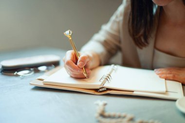 Koyu renk takım elbiseli, genç ve güzel bir kadın tatil zamanında kahve içerken iş planlarını günlüğe yazıyor. Planlama ve zaman yönetimi konsepti. Olumlu bir tavırla öğrenmek.