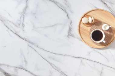 Düz kahve, süt ve badem kurabiyelerinin ahşap tepside altın parıltılarıyla bembeyaz mermer arka planda dekoratif yıldızların bileşimi yatıyordu. Minimum stil yılbaşı kahvaltısı ve mesaj yeri..