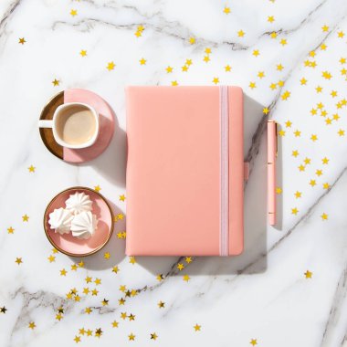 Metnin, kalemin, kahve fincanın, sütün, pembe kurdeleli küçük hediye kutun ve beyaz mermer masanda altın parıltılar için boş sayfaların olduğu defter. Yeni yıl ve Noel konsepti, en iyi manzara. Bayram kutlamaları