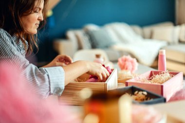 Genç bir kadın, el yapımı organik sabunlar, banyo tuzu, fırçalı sünger ve banyo bombalarını nedime hediye seti içine yerleştiriyor. Kadınların gününü güzelleştirmek için hediye kutuları..