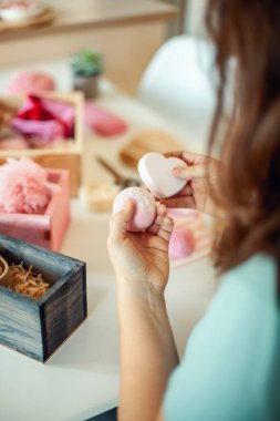 Kadın, kadın için pembe renkli kalp şeklinde hediye kutuları hazırlıyor organik doğal vücut bakımı kozmetikleri ve kadınlar için şekerli şekerlemeler, anneler günü ya da sevgililer günü. Nedime hediye kutusu fikri.