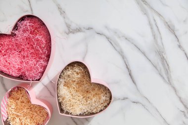 Pembe renkli kalp şekilli hediye kutularının üst görüntüsü ev yapımı banyo malzemeleri, lokum ve beyaz mermer arka plandaki kadınlar için vücut bakım ürünleri. Noel hediyeleri kavramı.