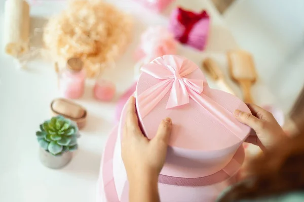 Woman hands holding pink colored heart shaped gift boxes of bath and body products for bridesmaids, bride and as a thoughtful gift for birthdays, anniversary, Valentine\'s Day, Mother\'s day, Christmas.