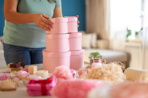 Woman hands holding pink colored heart shaped gift boxes of bath and body products for bridesmaids, bride and as a thoughtful gift for birthdays, anniversary, Valentine's Day, Mother's day, Christmas.