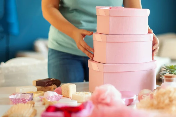 Woman hands holding pink colored heart shaped gift boxes of bath and body products for bridesmaids, bride and as a thoughtful gift for birthdays, anniversary, Valentine's Day, Mother's day, Christmas.